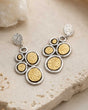 Turkish two-tone boho dangle earrings with hammered gold and silver discs, styled on stone surface with crystal