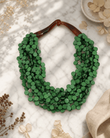 Twisted green wood disc pendant necklace on white marble surface