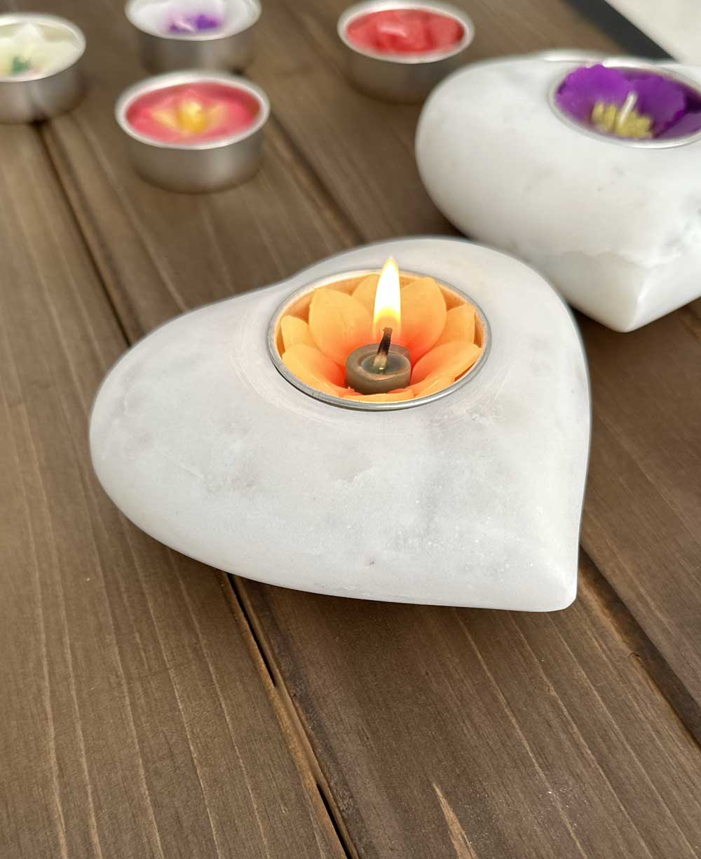 Close-up of a lit floral scented tealight in a white marble heart-shaped holder